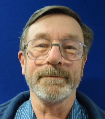 a man wearing glasses and smiling at the camera